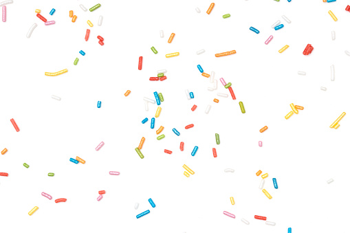 Colorful sprinkles spilled on white background.