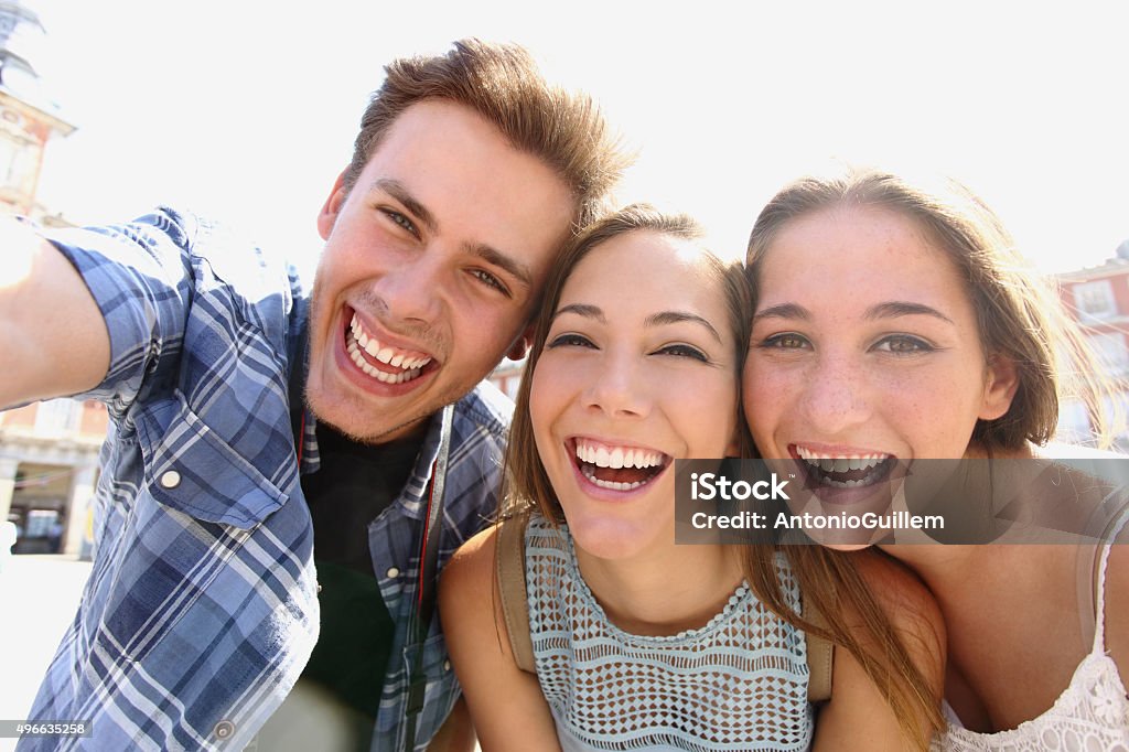 Group of teen friends taking a selfie Group of happy teen friends laughing and taking a selfie in the street 2015 Stock Photo