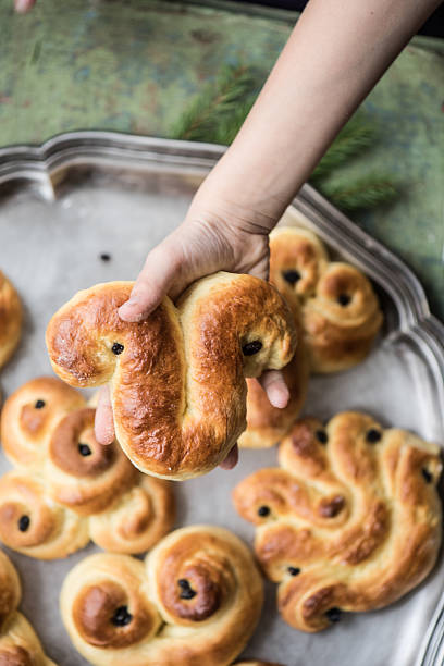 swedish saffron brötchen in kind hände - lucia bun stock-fotos und bilder