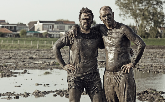 two male friends posing in mud