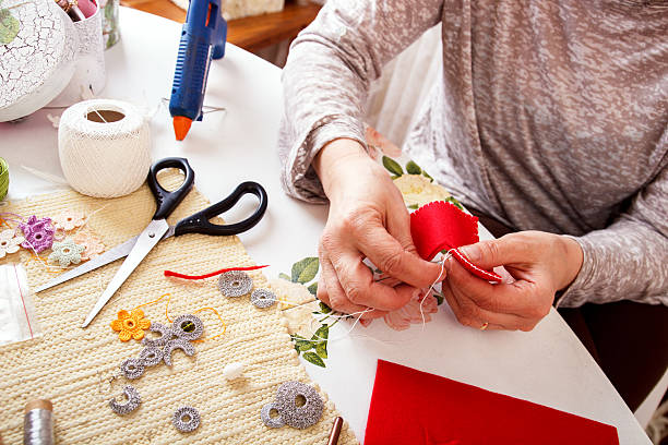 Senior women sews by hand Senior women sews by hand and making heart shape ornament. art and craft product stock pictures, royalty-free photos & images