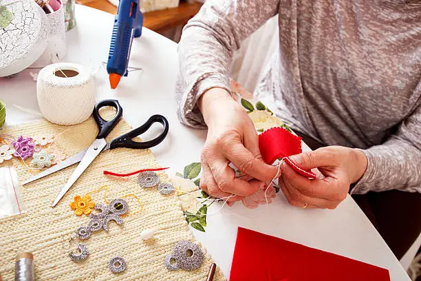 Photo of Senior women sews by hand