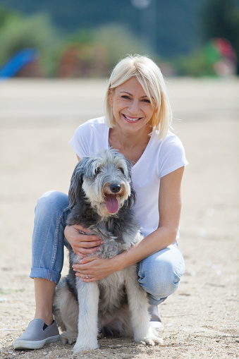 young smiling woman embracing her dog, looking at camera