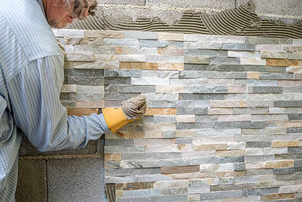 istock Older man decorating a wall with ornamental tiles 496658202
