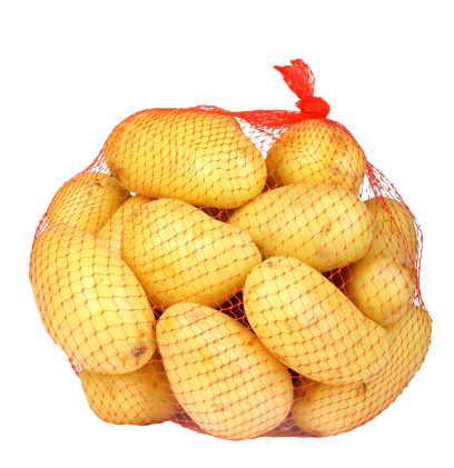 Heap of yellow raw potatos in red string bag. Isolated on white background. Close-up. Studio photography.