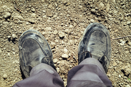 Footsie or feet selfie self photo of dirty worker shoes on the ground