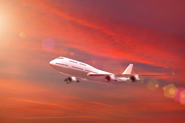 istock White airplane flying in sunset red sky 496662482