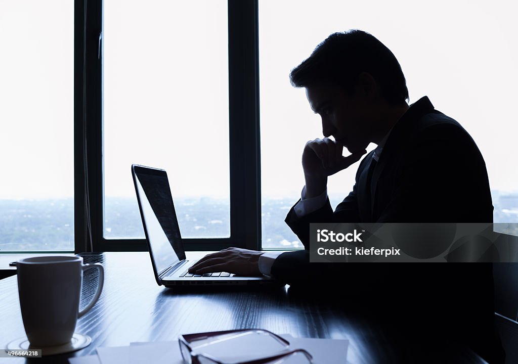 Businessman using laptop in the office Silhouette of businessman using laptop in the office. In Silhouette Stock Photo