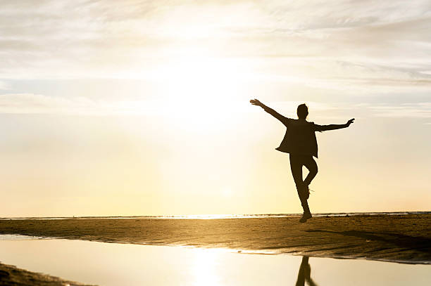 istock Young dancing girl silhouette in sunbeam at sunset 496664370