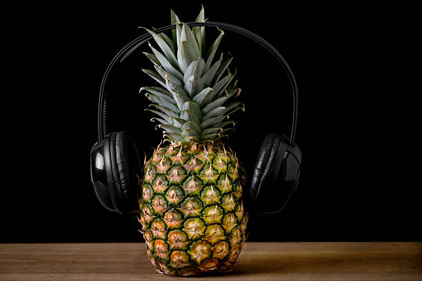 istock Pineapple with headphones on a wooden table 496675734