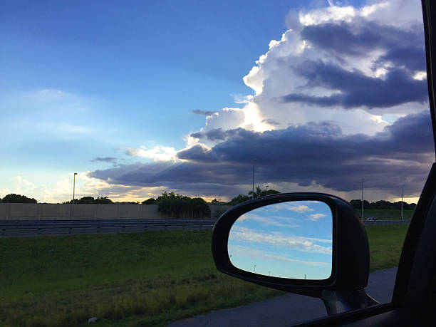 Car Rearview mirror reflecting blue sky with clouds, Sawgrass Expressway, Broward County, Florida