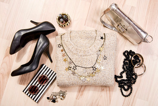 Woman black with gold and silver accessories, high heels, bracelets, necklace and nail polish.