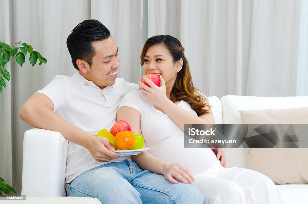 Healty eating of pregnant woman Asian pregnant woman eating an apple and looking at her husband Indonesian Ethnicity Stock Photo