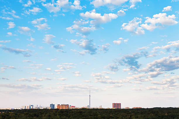 many small white clouds in blue sky over city in summer evening