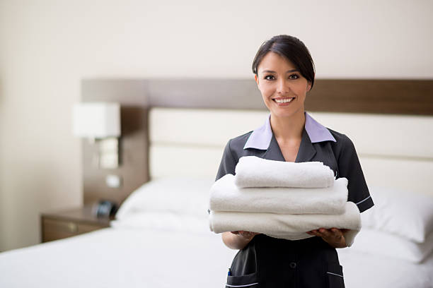 Maid working at a hotel Maid working at a hotel holding towels and looking at the camera smiling - housekeeping concepts housekeeping staff photos stock pictures, royalty-free photos & images