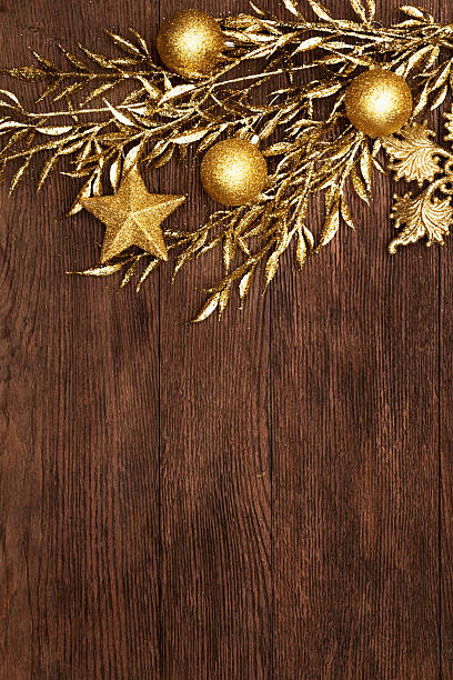 Vintage christmas background. Golden evening balls, stars and branch on dark brown wooden board.