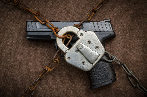Pistol behind lock and chains symbolic of gun control