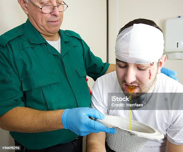 Patient Attended To By Paramedic Nurse Vomiting Into A Bowl Stock Photo - Download Image Now