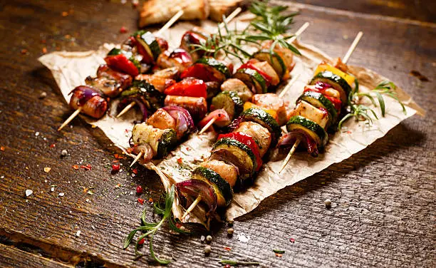 Grilled skewers with chicken meat, sausages, zucchini, peppers, onions and mushrooms in a herb marinade
