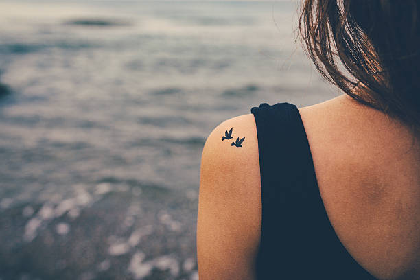 ragazza con uccelli un tatuaggio sulla spalla. concetto di libertà - tattoo women bird shoulder foto e immagini stock