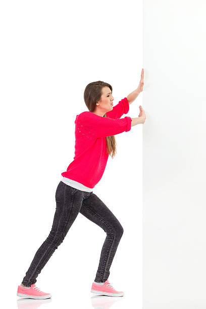 mujer joven empujando la pared - pushing women wall people fotografías e imágenes de stock