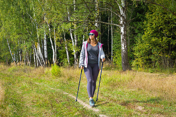 Young woman goes Nordic walking outdoors