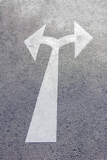 istock two way arrow symbol on a black asphalt road surface. 496702634