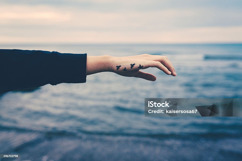 Girl with birds tattooed on the hand. Freedom concept Tattoo Stock Photo