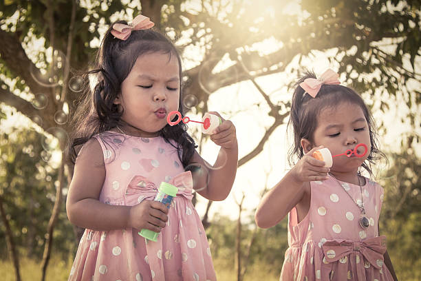 istock two cute little girls having fun blowing bubbles 496703602