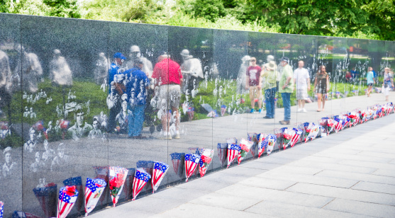 Washington, D.C. USA - May 23rd, 2014: Visitors and stainless steel statues that represent a squad on patrol are reflected in the polished granite wall. The Korean War Veterans Memorial in Washington, D.C. commemorates the sacrifices of the 5.8 million Americans who served in the U.S. armed services during the three-year period of the Korean War.