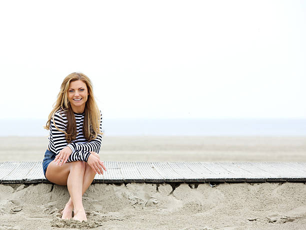 istock Happy young woman sitting at the beach 496705503