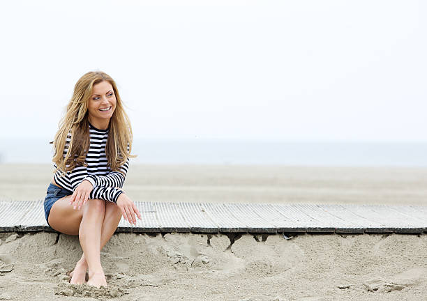 istock Smiling young blond woman sitting at the beach 496705505