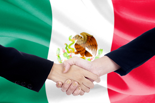 Image of two entrepreneurs shaking hands in front of Mexican flag