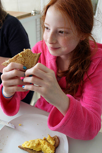 Young girl eating healthy breakfast in pink dressing gown
