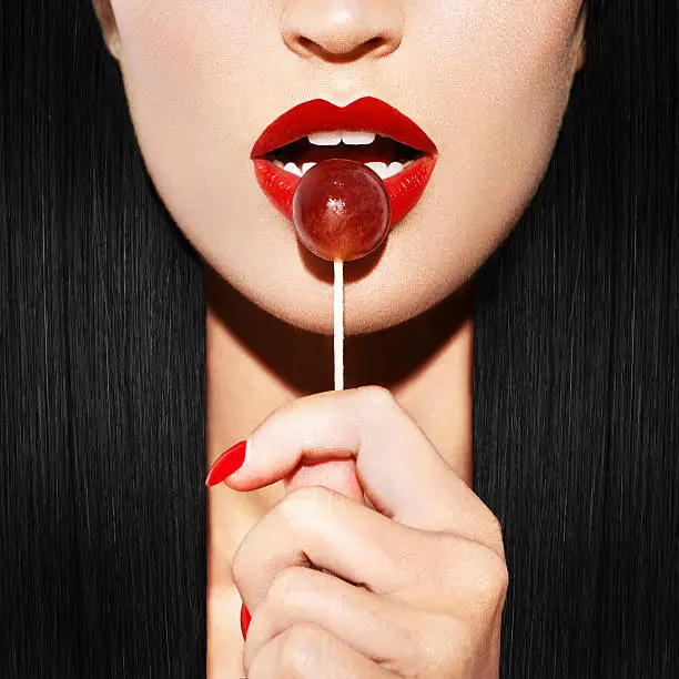 Woman with red lips holding lollipop, beauty closeup