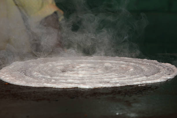 Dosa is a fermented crepe made from rice batter and black lentils, in South Indian Andhra Pradesh, Karnataka, Tamil nadu, Kerala. Man making hot dosa in traditional rural kitchen. Sambar, coconut chutney Sri Lanka