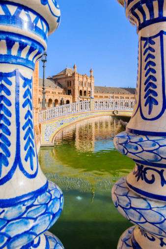 The Plaza de España, designed by Aníbal González, was a principal building built on the Maria Luisa Park's edge to showcase Spain's industry and technology exhibits. González combined a mix of 1920s Art Deco and 'mock Mudejar', and Neo-Mudéjar styles. The Plaza de España complex is a huge half-circle with buildings continually running around the edge accessible over the moat by numerous beautiful bridges. In the centre is a large fountain. By the walls of the Plaza are many tiled alcoves, each representing a different province of Spain.