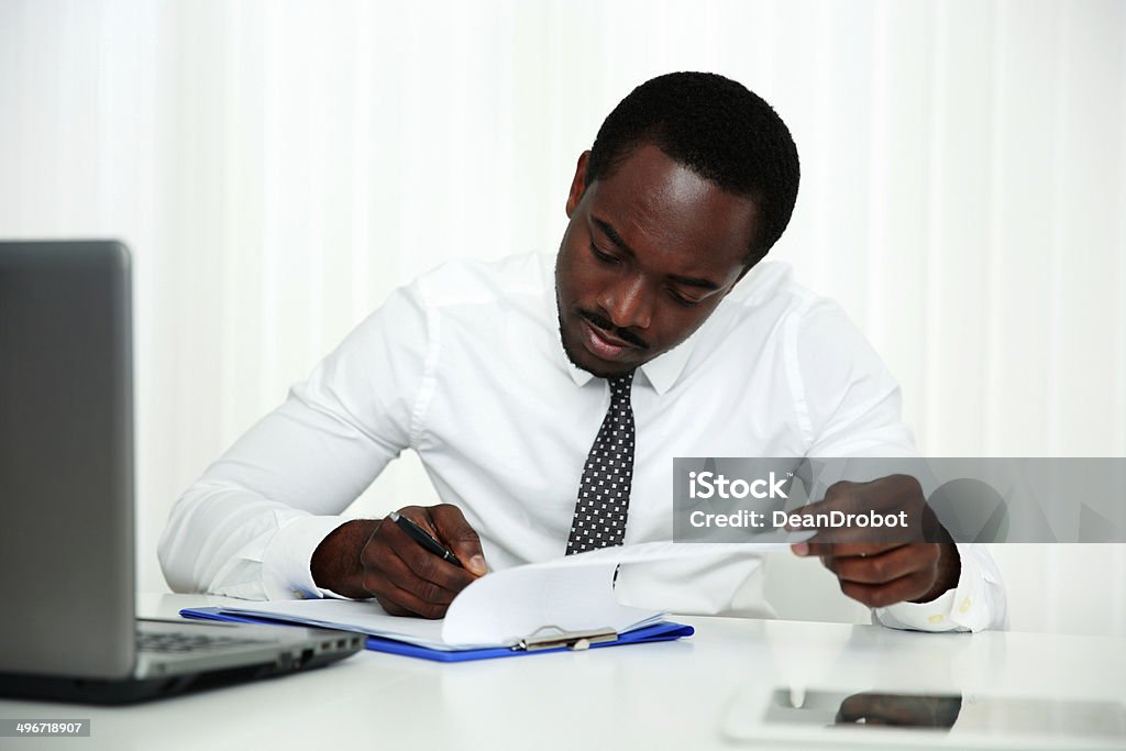 African man signing document African man signing document in office Adult Stock Photo