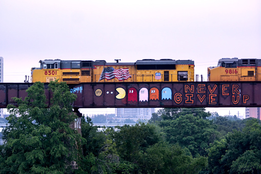 Austin, Texas, USA - June 01,2014: Early morning train on elevated tracks with graffiti, crossing Lady Bird Lake in downtown Austin, Texas as seen from the Lamar Street pedestrian bridge.