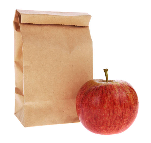обед в пикник-brown bag isolated on white with apple - lunch bag apple brown стоковые фото и изображения