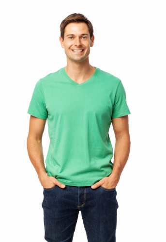 Portrait of happy young man standing with hands in pockets over white background. Vertical shot.
