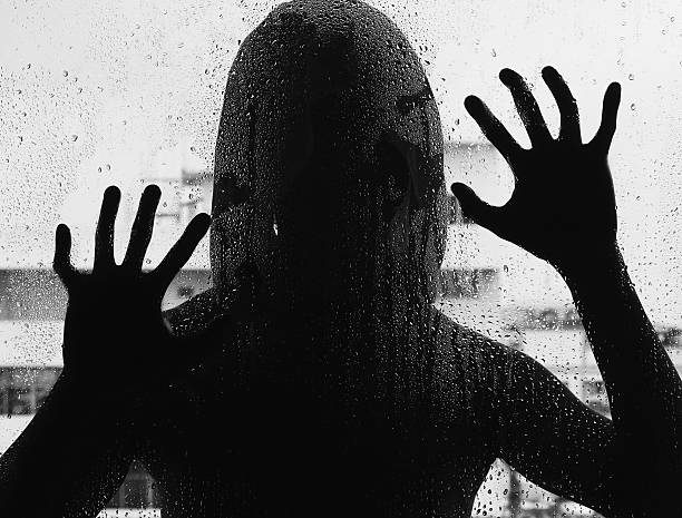 Shadowy figure with a knife behind glass,soft focus