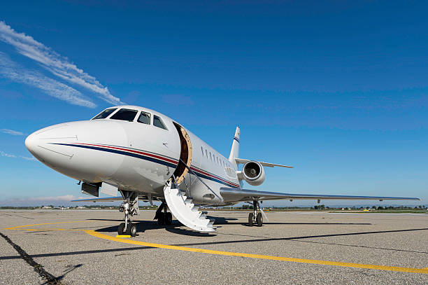 Airplane for private flights Low angle view of luxury airplane for private flights stationary on airport runway against blue sky. Private jet is ready to boarding with open vehicle door - boarding stairs. No people shot, front view composition and space for copy. airfield stock pictures, royalty-free photos & images