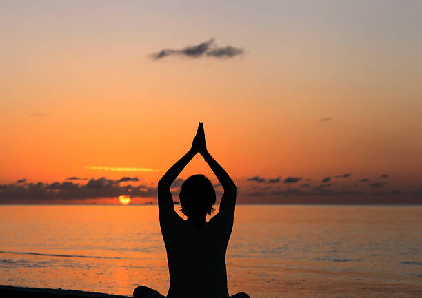 istock Silhouette of young man doing yoga at sunset 496730086