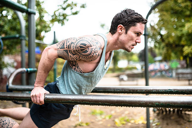 фитнес человек, делать упражнения в баре park - body building exercising one man only tattoo стоковые фото и изображения