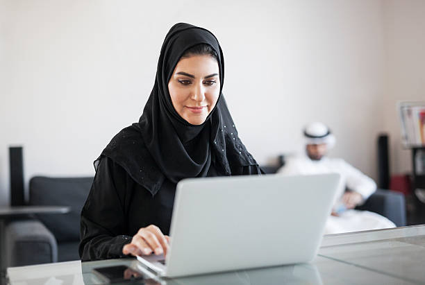 medio orientale donna utilizza il computer a casa - arabian peninsula immagine foto e immagini stock