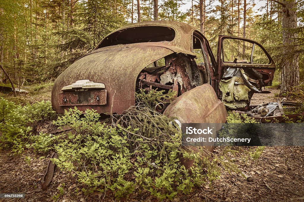 Old rusted scrap car in a forest Retro styled image of an old rusted and weathered scrap car in a forest Car Stock Photo