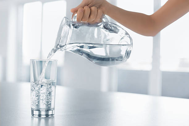 お水をご用意。女性の手を注ぐ水からグラスにピッチャー - water women glass healthy eating ストックフォトと画像