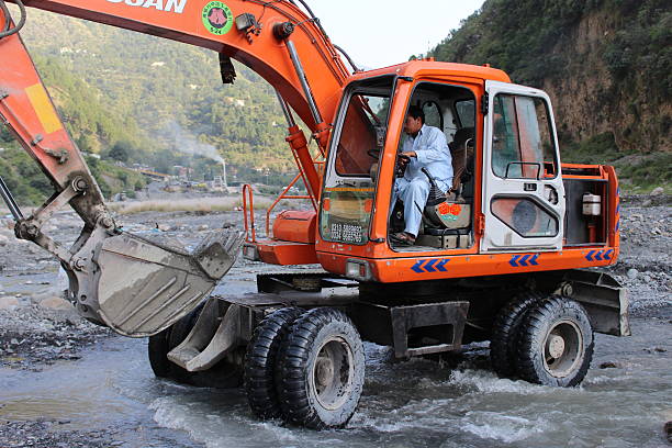 Trencher Harnui, Abbottabad, Pakistan - September 13, 2015: A man working a trencher in the Asphalt project in Harnui river, Abbottabad, Pakistan. abbottabad stock pictures, royalty-free photos & images
