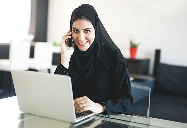 istock Charming Arab Woman Talking on Phone and Using Laptop 496736288